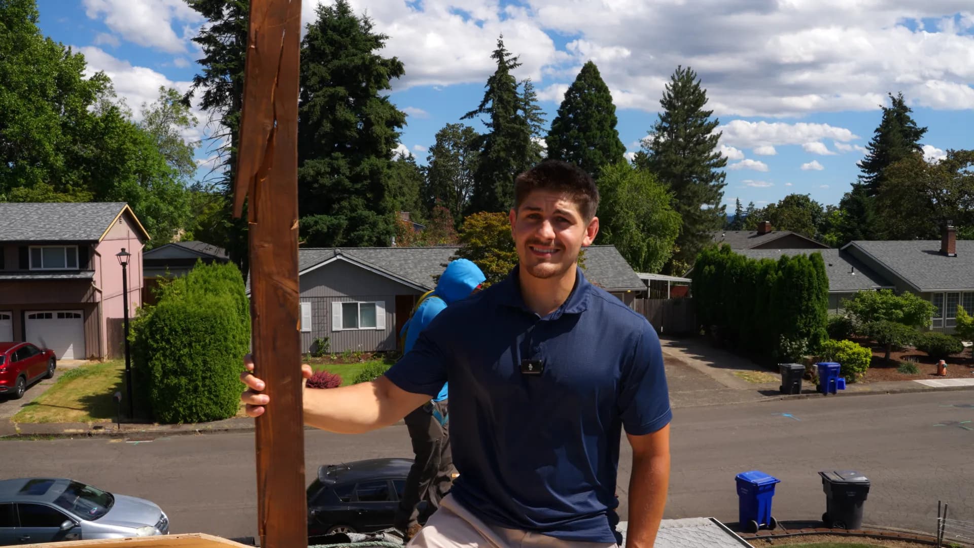 Crew member holding up a split wooden rafter removed from a roof in Gladstone, OR