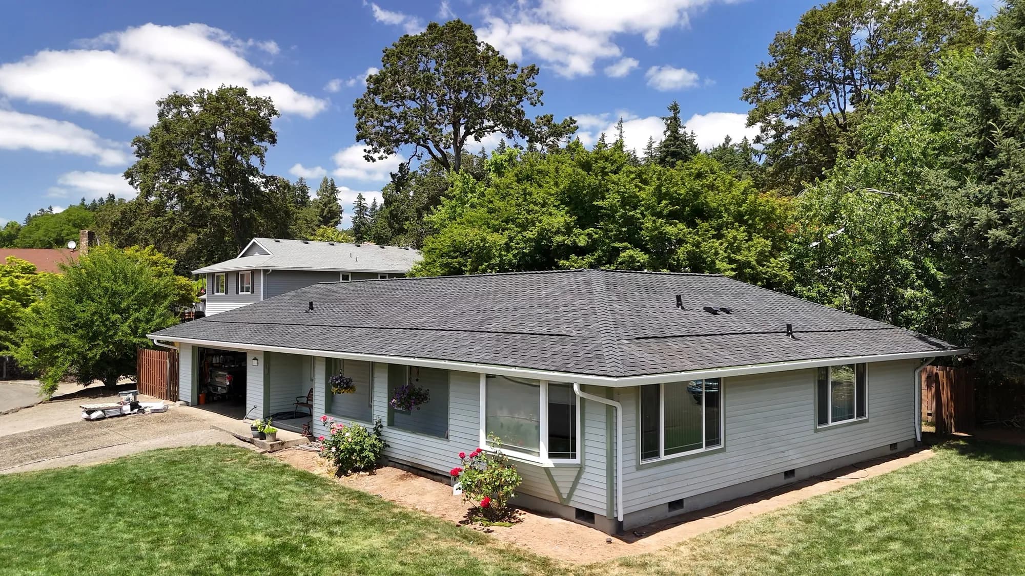 Aerial view of the front of a single-story house with a new dark gray shingle roof in Gladstone, OR