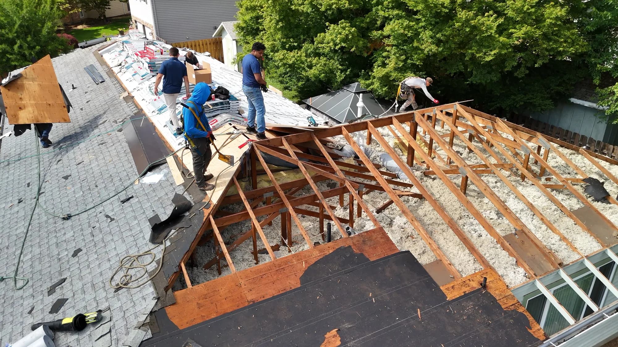 Aerial view of a roof mid-replacement with old shingles on one slope and exposed rafters on the other in Gladstone, OR
