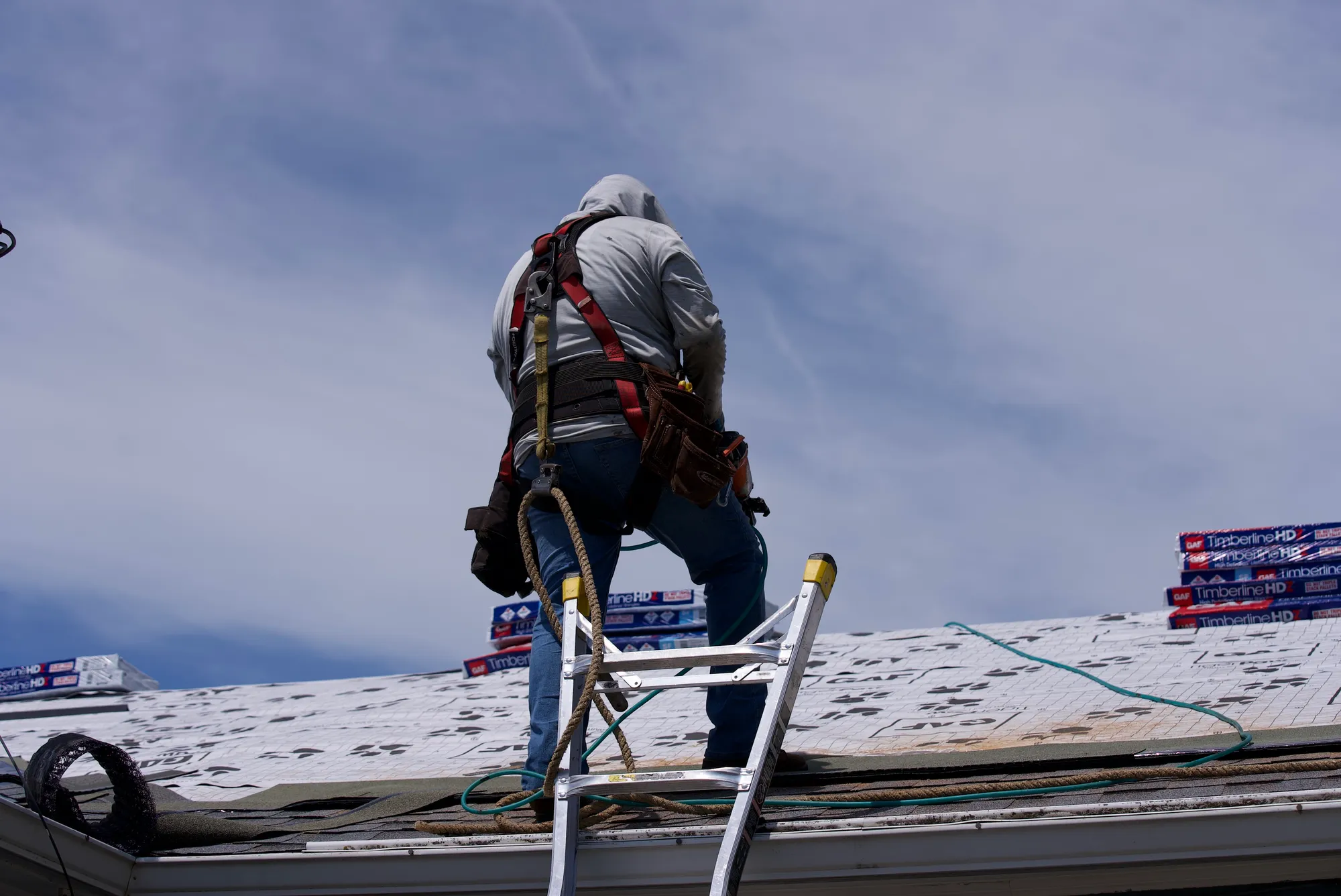 Harnessed Cornerstone roofer installing shingles on a Hillsboro, OR roof
