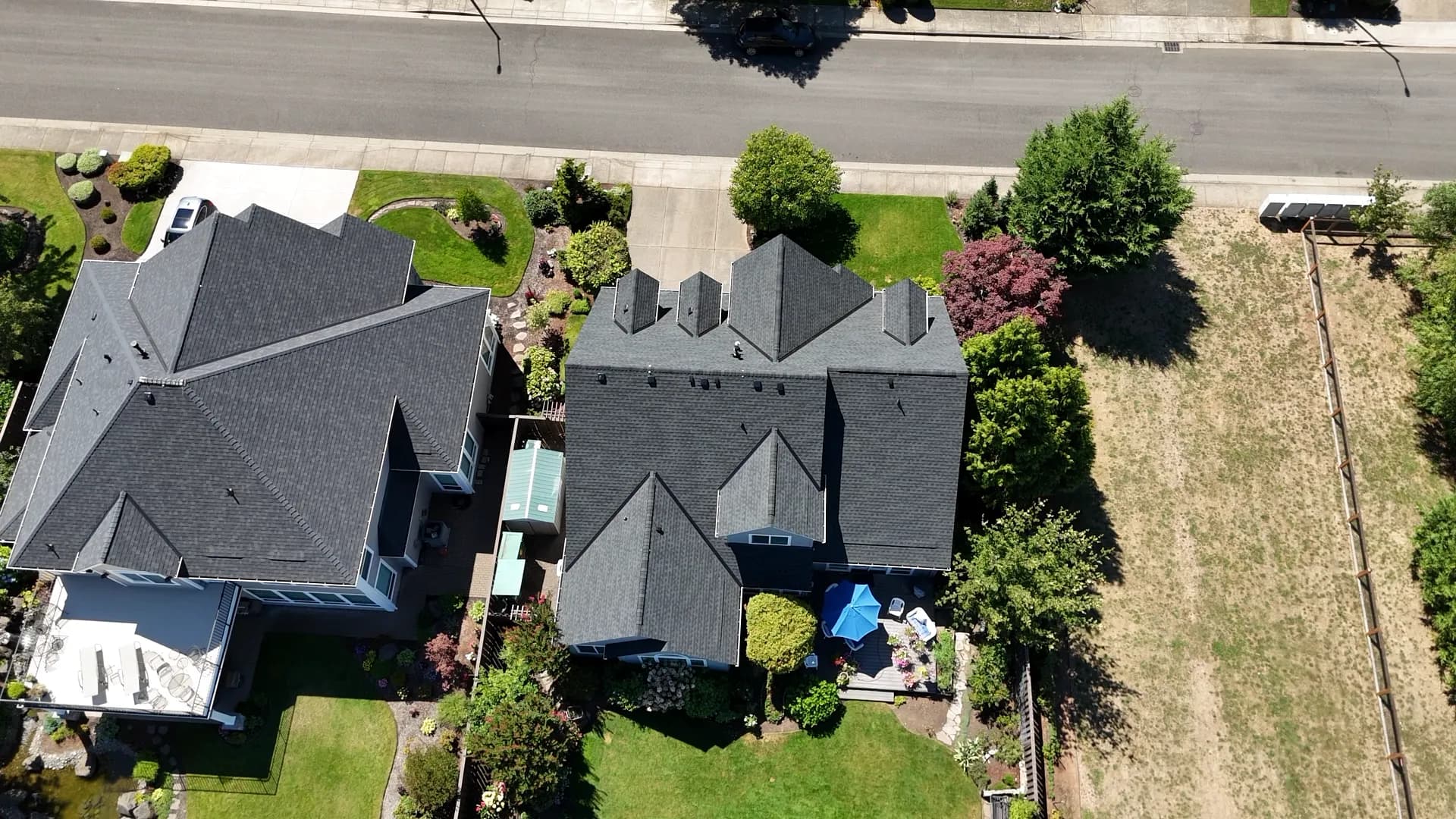 Top-down aerial view of two neighboring houses with dark shingle roofs on a suburban street in Salem, OR