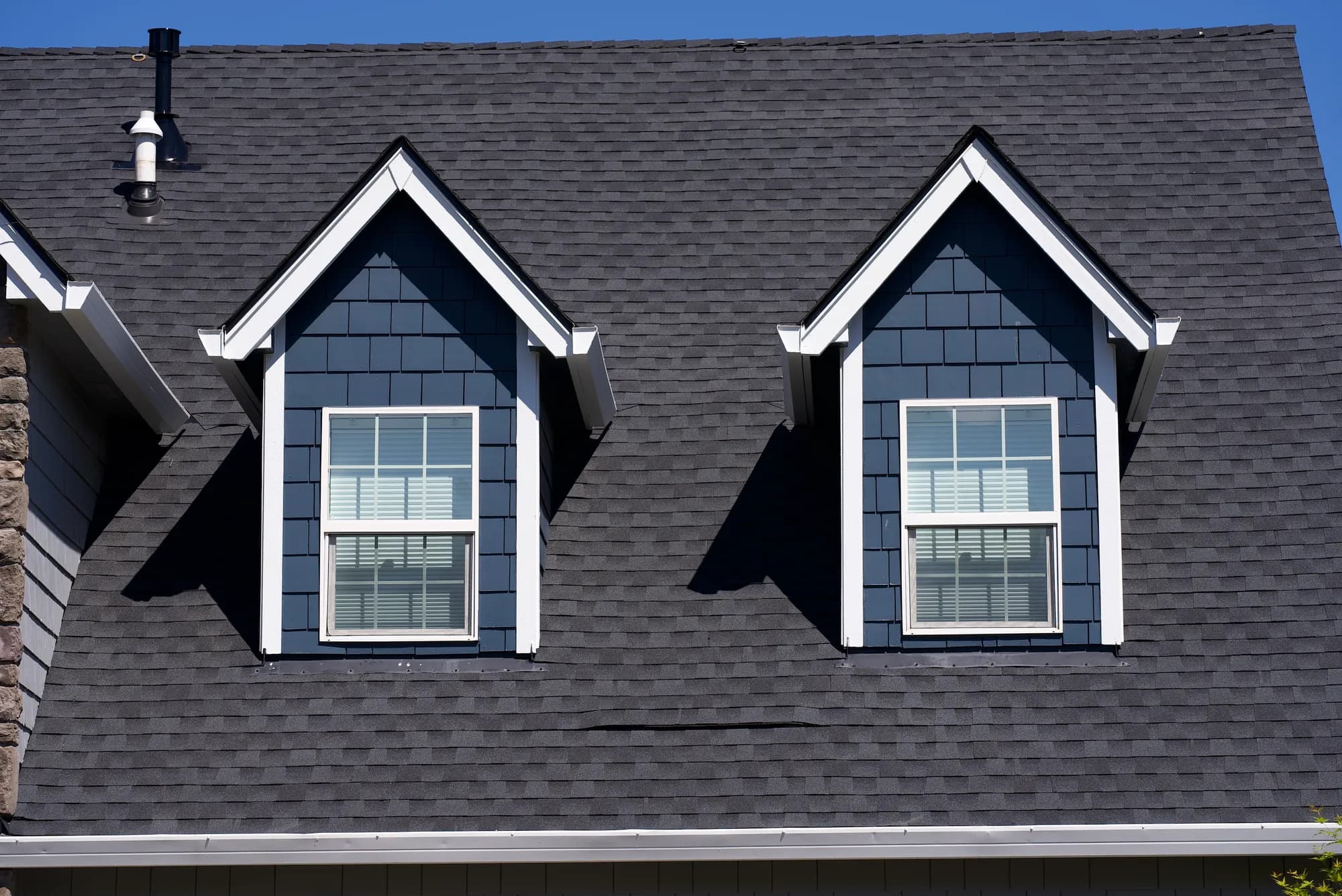 Straight-on view of two gabled dormers with blue shake siding and white trim on a new charcoal shingle roof in Salem, OR