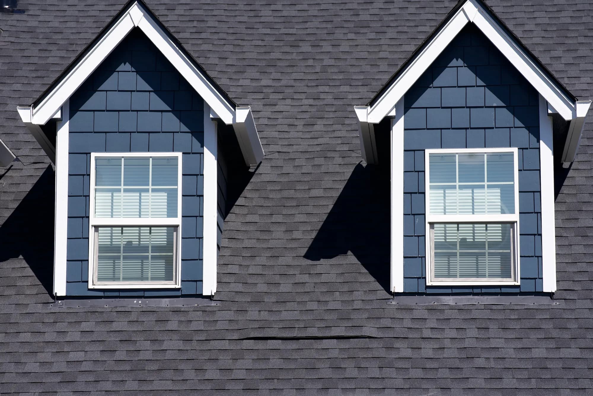 Straight-on close view of two gabled dormers with blue shake siding on a new charcoal shingle roof in Salem, OR