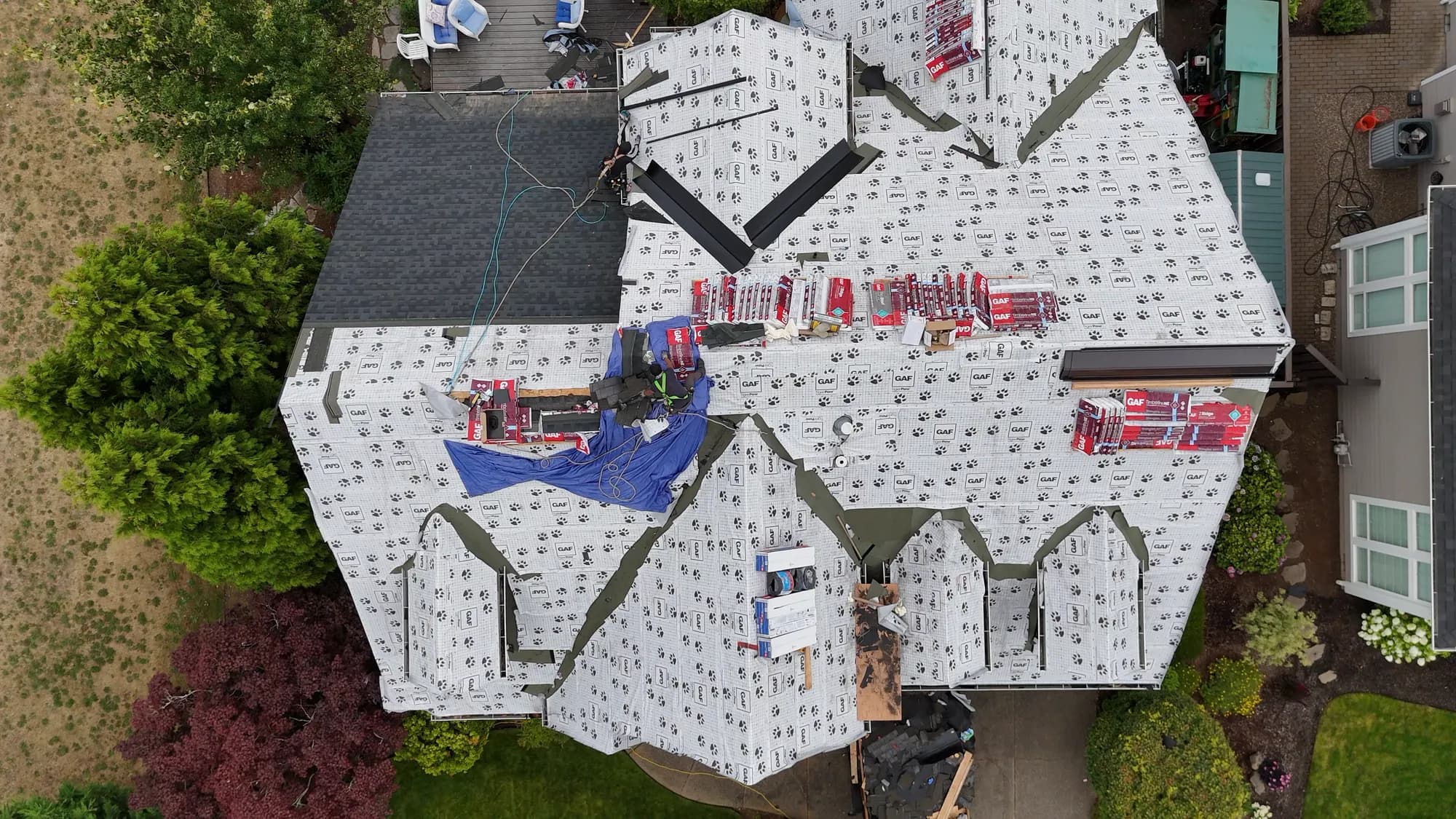 Top-down aerial view of a roof mid-replacement covered in GAF Tiger Paw underlayment with shingle bundles staged at the ridges in Salem, OR