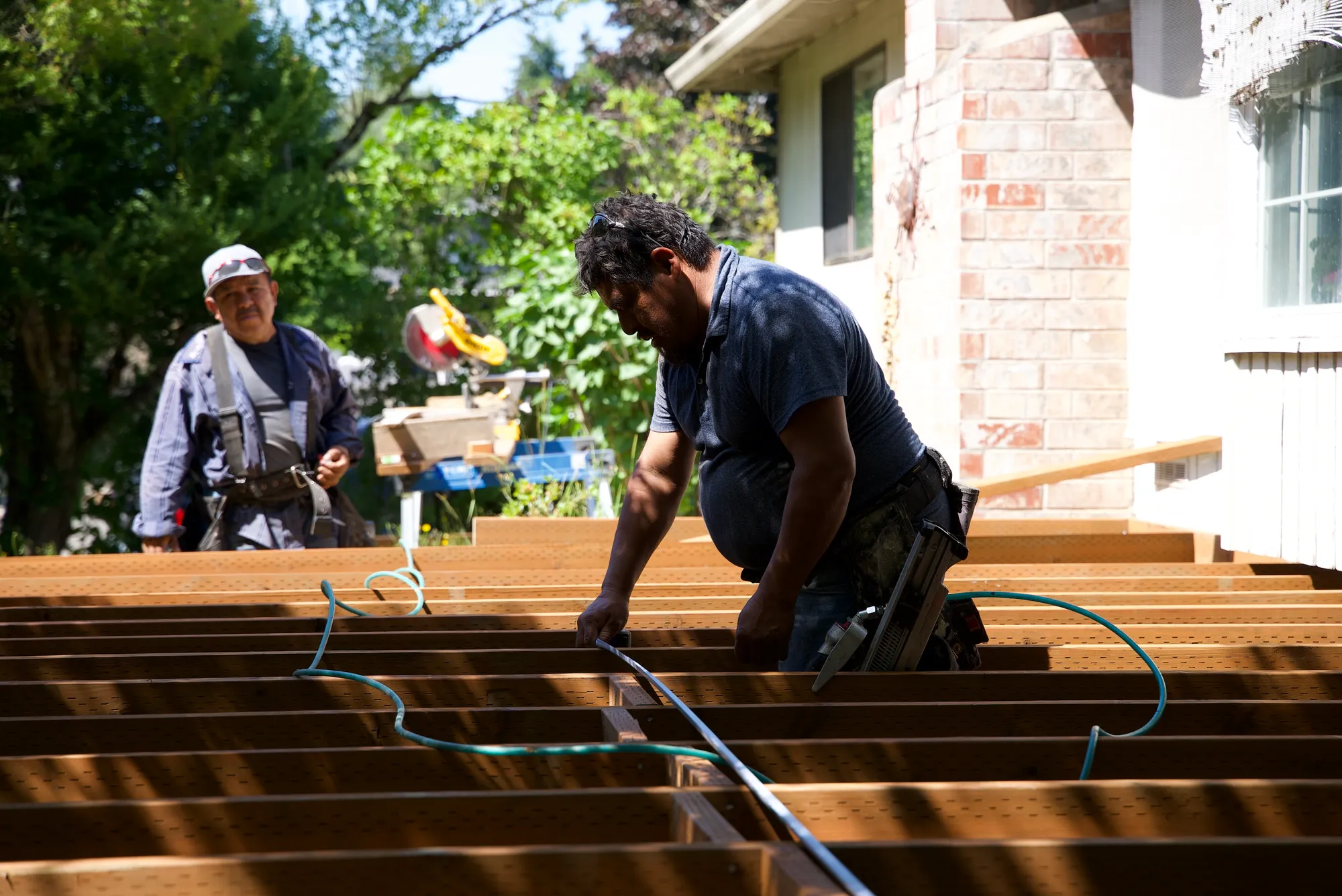 Close view of a worker fastening wooden deck joists with a pneumatic nail gun in Tualatin, OR