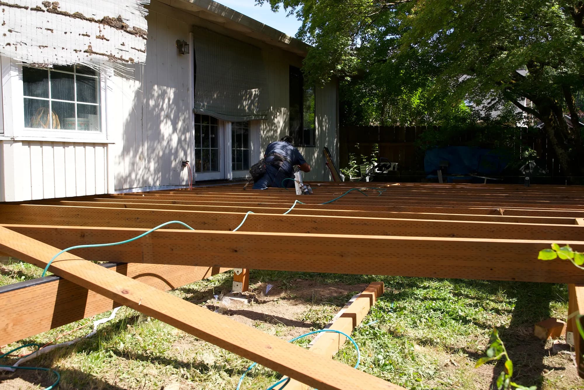 Wide view of a deck frame of parallel wooden joists attached to a house at the ledger board in Tualatin, OR