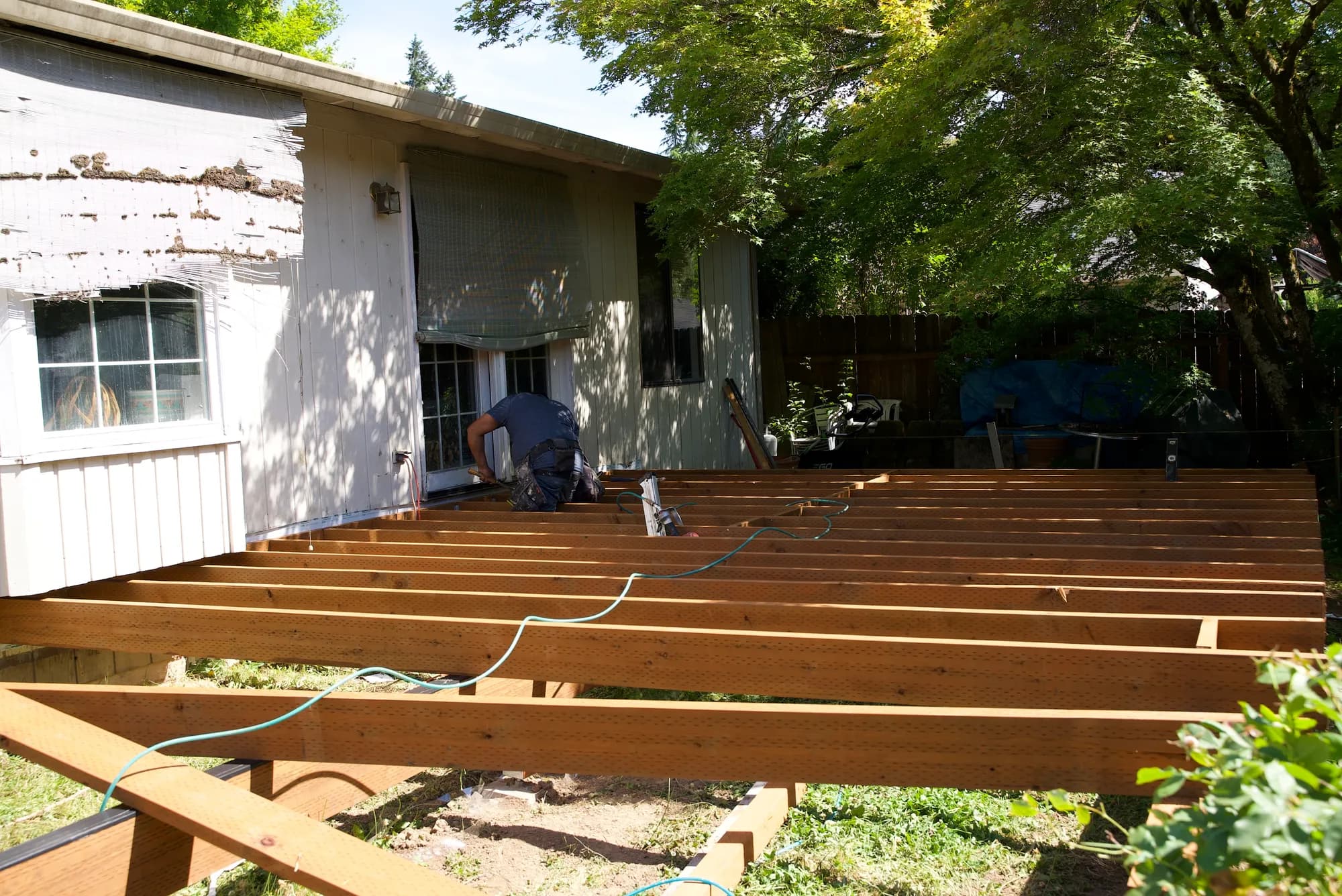 Wide view of wooden deck joists spanning from a house toward a fenced backyard in Tualatin, OR