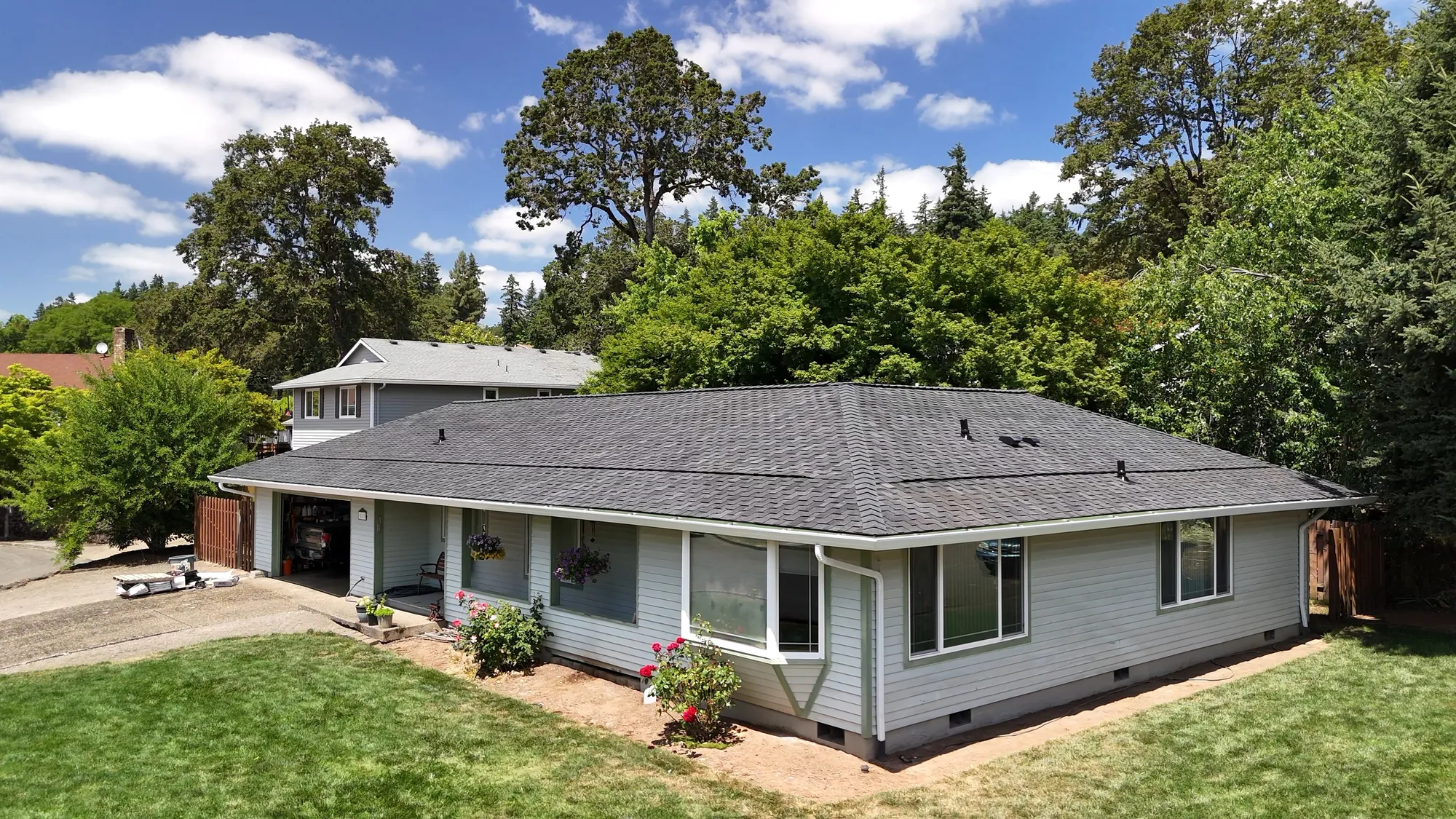 Aerial view of a completed dark gray shingle roof on a single-story Gladstone, OR home