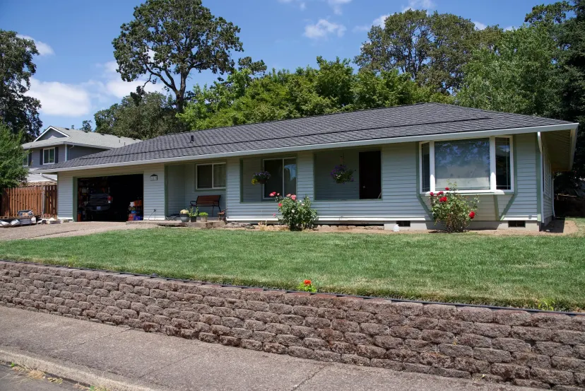 Ranch home in Gladstone, OR with new light blue lap siding, white gutters, and a dark gray shingle roof