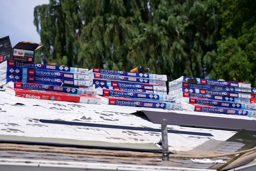 Stacks of GAF Timberline HDZ and Z Ridge shingle bundles on a roof covered in printed underlayment in Hillsboro, OR